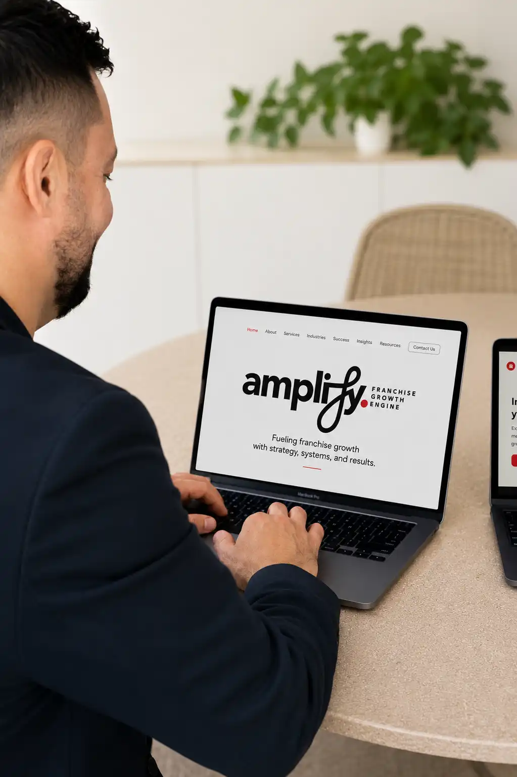 Man working on a laptop displaying a franchise growth website with a modern business workspace background.
